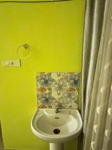 a bathroom with a white sink and a yellow wall at Mon Aashray Stay in Guwahati +39 photos