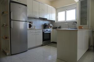 a kitchen with white cabinets and a stainless steel refrigerator at El Condor Casa in Rhodes Town