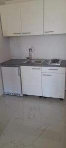 a kitchen with white cabinets and a sink at ELA Apartmani i sobe in Neum