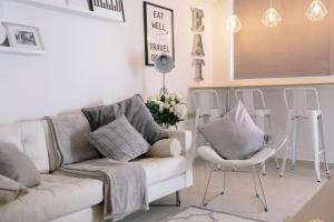 a living room with a white couch and chairs at Studio Apartment By Travel Lets Holiday Homes Lagada With Pool in Makry Gialos