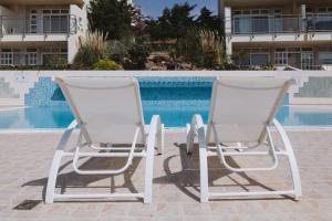 two chairs sitting next to a swimming pool at Studio Apartment By Travel Lets Holiday Homes Lagada With Pool in Makry Gialos