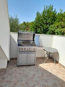 a outdoor kitchen with a grill and a table at ELA Apartmani i sobe in Neum