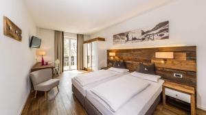 ein Schlafzimmer mit einem großen Bett mit hölzernem Kopfteil in der Unterkunft Hotel ANDER in Bruneck + 86 Fotos