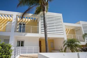 a white house with a palm tree in front of it at Villa Granada by Algarve Holidays in Almancil