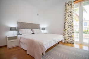 a white bedroom with a bed and a window at Villa Granada by Algarve Holidays in Almancil +46 photos