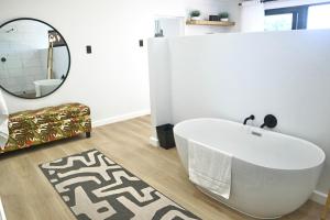 a bathroom with a white tub and a mirror at Chintsa Oceanfront in Chintsa +36 photos