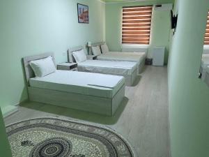 a room with two beds and a rug at Mahdiy Hotel in Khiva