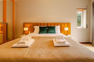 a bedroom with a large bed with two towels on it at Caldas Charm Getaway - Garden Terrace & Comfort in Caldas da Rainha