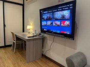 a flat screen tv hanging on a wall with a desk at Roxy Apartment Kuching in Kuching