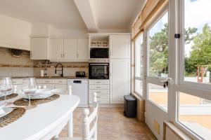 a kitchen with white cabinets and a large window at Caldas Charm Getaway - Garden Terrace & Comfort in Caldas da Rainha