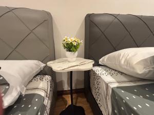 two beds with a table with a vase of flowers at Roxy Apartment Kuching in Kuching