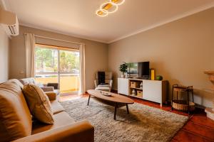 a living room with a couch and a table at Caldas Charm Getaway - Garden Terrace & Comfort in Caldas da Rainha