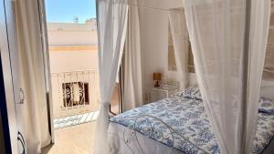a bedroom with a canopy bed and a balcony at Al centro con panorama Favignana Isole Egadi in Favignana