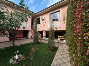 a pink building with a yard with a bench in it at Hotel & Hostel Siyob Samarkand in Samarkand