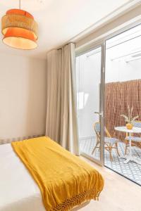 a bedroom with a yellow blanket on a bed with a balcony at Lumen Mare Malvarrosa by SH Hoteles in Valencia