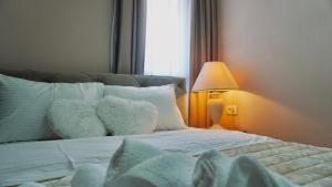 a bedroom with a bed with white pillows and a lamp at Apartments St Jakov in Međugorje