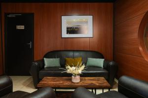 a living room with a leather couch and a table at Logis Hôtel Le Relais in Biscarrosse