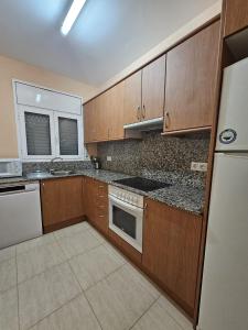a kitchen with wooden cabinets and a white refrigerator at MEDDAYS Villa BERLÍN in Miami Platja