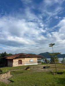 an old house sitting in a field next to a lake at ImuHira Campsite in Nyamasheke