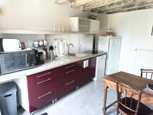 a kitchen with red cabinets and a microwave and a table at Maison les Alouettes in Nevers