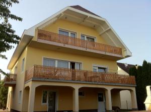 a yellow house with a balcony on top of it at Sárga Apartman Ház in Balatonfüred