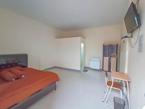 a bedroom with a bed and a chair and a tv at Verisha Inn Singkawang RedPartner in Singkawang