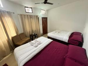 a hotel room with two beds and a chair at Kedar Mount View in Sonprayag