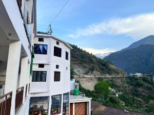 a white building with a view of a mountain at Kedar Mount View in Sonprayag