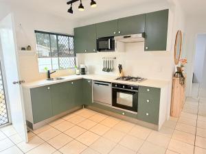 a kitchen with green cabinets and a tile floor at 'Your Place on Davidson' Uno in Mount Isa