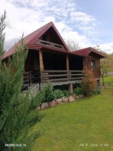 a log cabin with a green yard in front of it at Wooden House "Una" in Kulen Vakuf