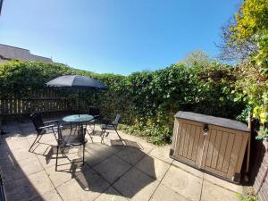 a patio with a table and chairs and an umbrella at 2 beds, AC, fully enclosed patio, private parking in Poole