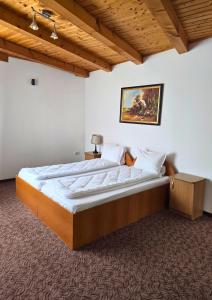 a large bed in a bedroom with a wooden ceiling at Vila Pufu in Slănic-Moldova