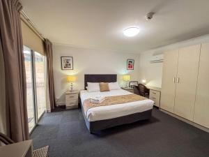 a bedroom with a bed and a large window at Gracelands Parkes in Parkes