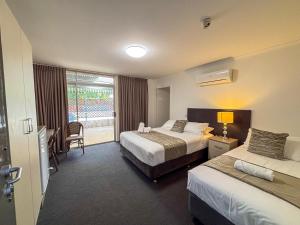 a hotel room with two beds and a window at Gracelands Parkes in Parkes