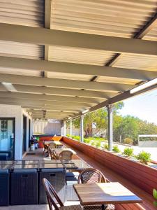 an outdoor patio with tables and chairs and a roof at Gracelands Parkes in Parkes