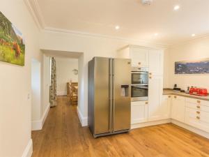 a stainless steel refrigerator in a kitchen with white cabinets at 6 Bed in Strathcarron oc-ca343 in Applecross