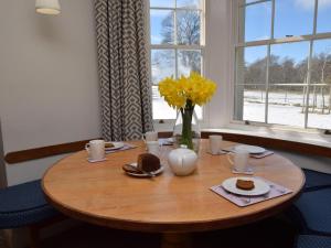 a wooden table with food and a vase with yellow flowers at 2 Bed in Applecross oc-ca422 in Applecross