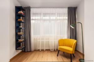 a yellow chair in a room with a window at Apartament Nordic 3 in Gura Humorului +4 photos