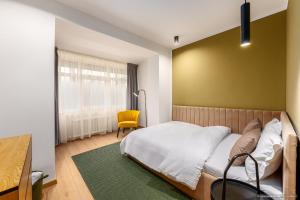 a bedroom with a large bed and a yellow chair at Apartament Nordic 3 in Gura Humorului
