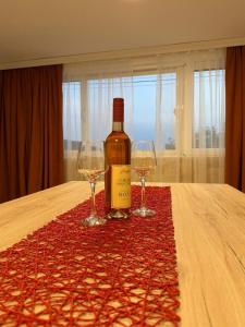 a bottle of wine and two wine glasses on a table at Apartmani ,,Merlin,, in Utjeha