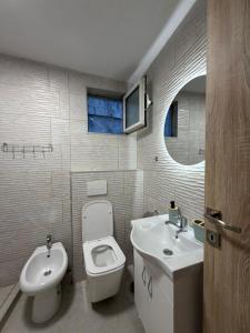 a bathroom with a white toilet and a sink at Apartmani ,,Merlin,, in Utjeha +5 photos