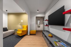 a living room with a tv and a yellow chair at Apartament Nordic 3 in Gura Humorului