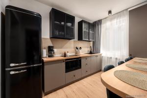 a kitchen with a black refrigerator and a table at Apartament Nordic 3 in Gura Humorului