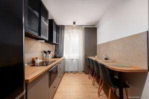 a kitchen with a long bar with chairs in it at Apartament Nordic 3 in Gura Humorului
