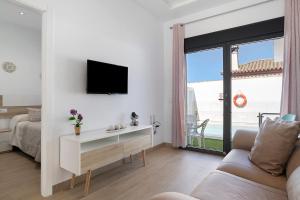 a white living room with a tv and a couch at Casas Las Arenas 2 in Conil de la Frontera