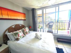a bedroom with a bed with a teddy bear on it at OceanFront- Whale Watch- On Beach- Stunning in Umdloti +35 photos