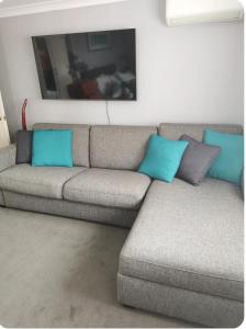 a gray couch with blue pillows in a living room at Tiki Hut in Tauranga