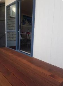 a wooden deck with a sliding door and a table at Tiki Hut in Tauranga