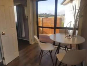 a white table and chairs in a room with a window at Tiki Hut in Tauranga