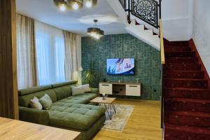 a living room with a green couch and a staircase at Royal Crown Apartments in Subotica